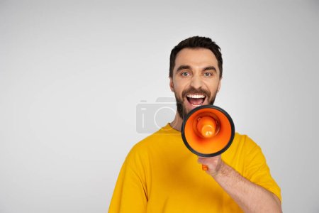 Photo pour Excité homme criant dans mégaphone et regardant caméra isolé sur gris - image libre de droit