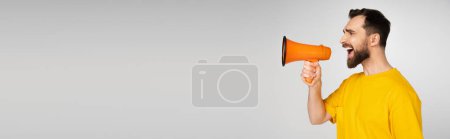 side view of displeased bearded man screaming in megaphone isolated on grey, banner mug #621217444