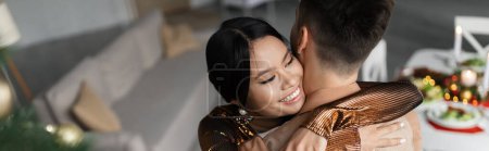 Hochwinkelaufnahme von fröhlichen asiatischen Frau umarmt Ehemann während Weihnachtsfeier, Banner