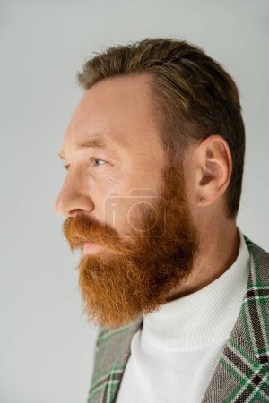 Bearded man in plaid jacket looking away isolated on grey 