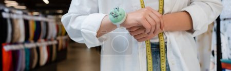 Photo for Partial view of seller with measuring tape and needle cushion on hand in textile shop, banner - Royalty Free Image