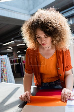 Photo for Curly customer touching cloth samples on table in textile shop - Royalty Free Image
