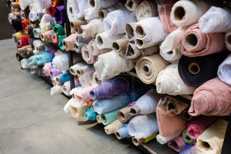 Colorful fabric rolls on shelves in textile shop 