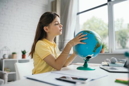 Brünettes Mädchen lernt zu Hause Geografie und schaut auf Globus