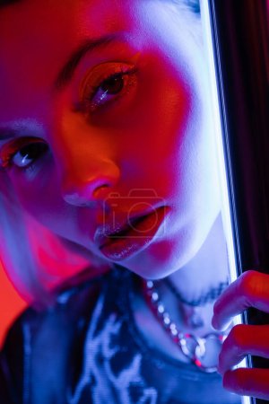 close up portrait of young and pretty woman with makeup near luminous neon lamp 