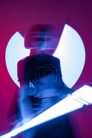 Téléchargez les photos : Longue exposition de femme floue avec des lampes au néon vibrantes sur fond violet - en image libre de droit
