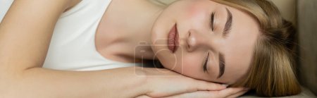 Téléchargez les photos : Jeune femme blonde avec les yeux fermés dormant sur le canapé à la maison, bannière - en image libre de droit