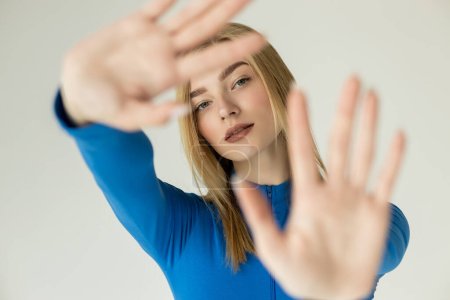 woman with blurred outstretched hands looking at camera isolated on grey