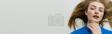 Photo for Top view of pretty woman touching chin and looking away while lying on grey background, banner - Royalty Free Image
