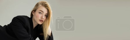 Photo for Portrait of sensual blonde woman in black jacket looking at camera isolated on grey, banner - Royalty Free Image