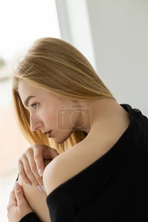 perfil de mujer rubia seductora con hombro desnudo posando en casa