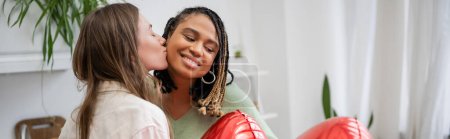 glücklich lesbische Frau küsst die Wange ihrer afrikanisch-amerikanischen Freundin in der Nähe roter Luftballons am Valentinstag, Banner