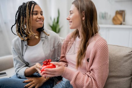 Téléchargez les photos : Gai afro-américain et lesbienne femme donnant en forme de coeur cadeau à petite amie - en image libre de droit