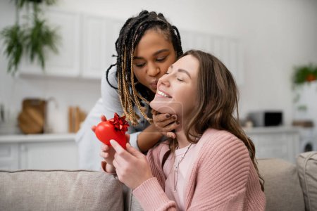 Téléchargez les photos : Africaine américaine lesbienne femme baisers joyeuse copine avec rouge en forme de coeur présent - en image libre de droit