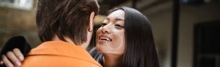 Photo for Young asian woman hugging and whispering to boyfriend on terrace of cafe, banner - Royalty Free Image