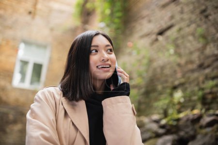 Positive asiatische Frau telefoniert in Outdoor-Café 