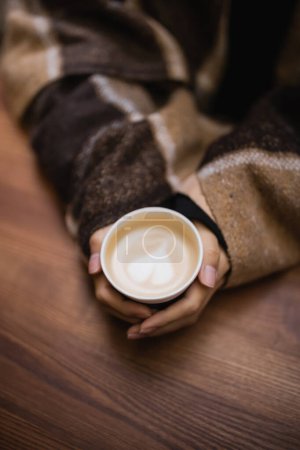 Draufsicht von Frau in Decke mit Cappuccino in Outdoor-Café 