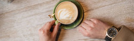 Photo for Top view of cropped man holding cup of cappuccino with latte art, banner - Royalty Free Image