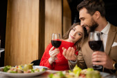 young woman and cheerful man holding glasses with red wine during celebration on valentines day  Mouse Pad 631516446