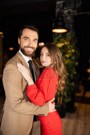 Lächelnder Mann und Frau in festlicher Kleidung umarmen sich am Valentinstag 