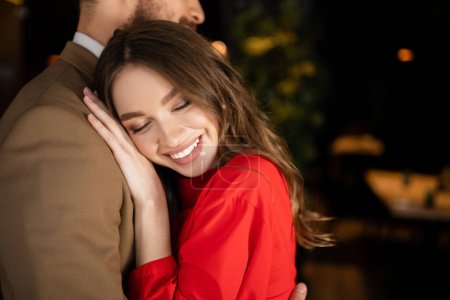 Junger Mann und fröhliche Frau in festlicher Kleidung umarmen sich am Valentinstag 