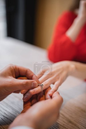 cropped view of man wearing engagement ring on finger of girlfriend on valentines day 