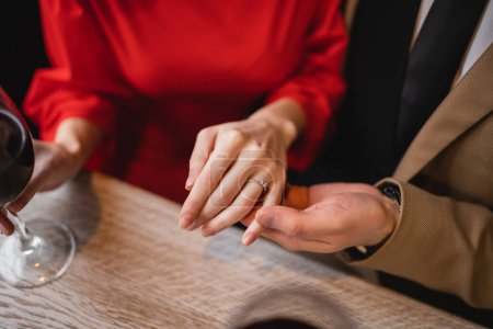 Ausgeschnittene Ansicht eines Mannes, der am Valentinstag die Hand einer Frau mit Verlobungsring am Finger hält 