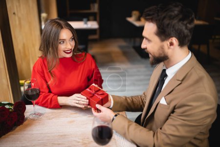 high angle view of bearded man holding wrapped present near happy woman on valentines day 