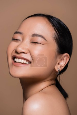 Pretty asian woman with closed eyes posing isolated on brown 