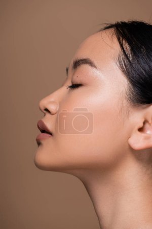 Photo for Side view of young asian woman with natural makeup isolated on brown - Royalty Free Image