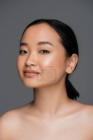 Foto de Young asian woman with naked shoulders looking at camera isolated on grey - Imagen libre de derechos