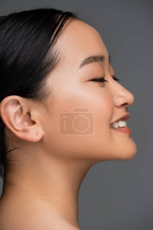 Téléchargez les photos : Side view of smiling asian woman closing eyes isolated on grey - en image libre de droit