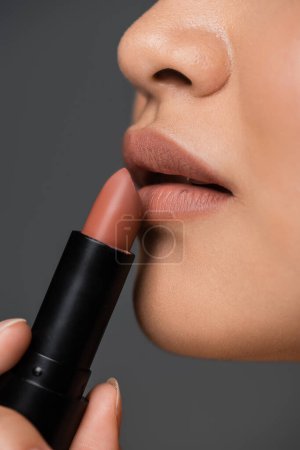 Photo for Close up view of woman applying beige lipstick isolated on grey - Royalty Free Image