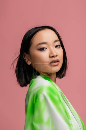 Foto de Portrait of young asian woman with makeup looking at camera isolated on pink - Imagen libre de derechos