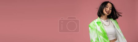 Photo for Young asian woman in trendy jacket and makeup looking at camera while posing isolated on pink, banner - Royalty Free Image