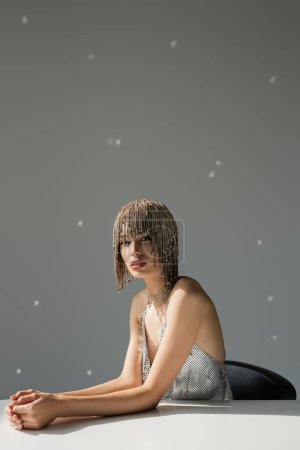 Photo for Young model with metallic jewelry headwear posing while looking at camera on grey - Royalty Free Image
