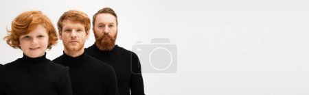 Photo for Redhead men in black sweaters looking at camera near happy boy isolated on grey, banner - Royalty Free Image
