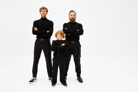 Photo for Full length of redhead men and boy in black clothes posing with crossed arms on light grey background - Royalty Free Image