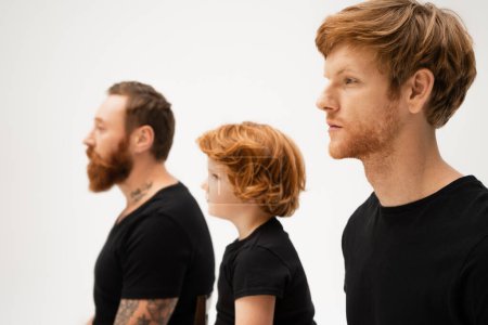 Photo for Side view of redhead boy near dad and bearded grandfather in black t-shirts isolated on grey - Royalty Free Image
