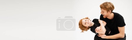 Téléchargez les photos : Joyful redhead man having fun with cheerful son crossing arms isolated on grey, banner - en image libre de droit