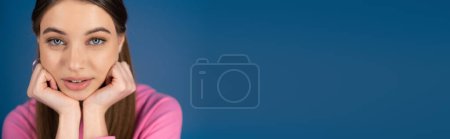 Téléchargez les photos : Portrait of brunette teenager looking at camera isolated on blue, banner - en image libre de droit
