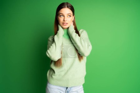 Foto de Young teen girl in jumper looking away on green background - Imagen libre de derechos