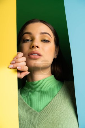 Low angle view of teenager with makeup looking at camera on colorful background 