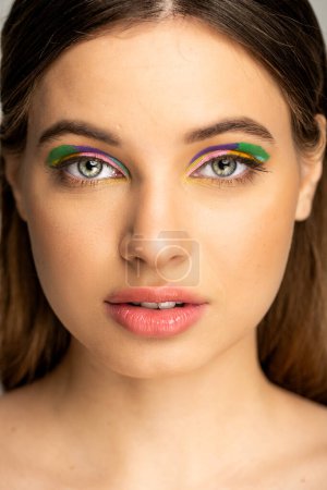 Téléchargez les photos : Teenage girl with colorful makeup looking at camera isolated on grey - en image libre de droit