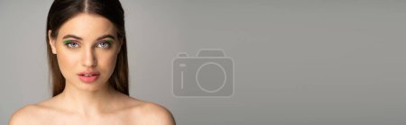 Pretty brunette teenager with colorful makeup standing isolated on grey, banner 