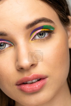 Téléchargez les photos : Cropped view of teen model with multicolored makeup looking at camera isolated on grey - en image libre de droit