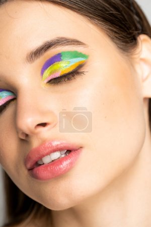 close up view of teenage model with colorful eyeshadows and closed eyes 