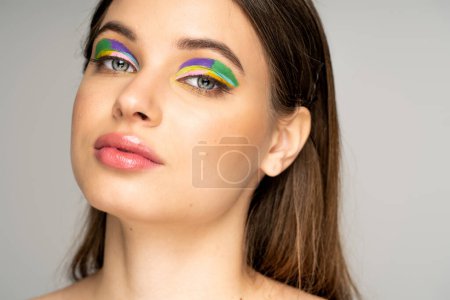 Téléchargez les photos : Teen girl with multicolored eyeshadows looking at camera isolated on grey - en image libre de droit