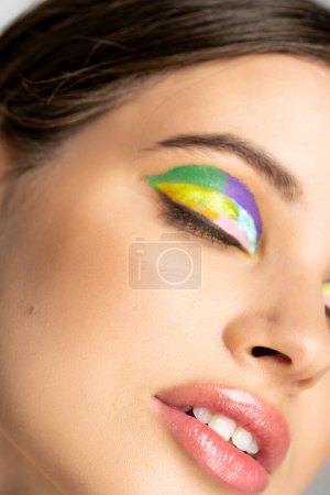 Cropped view of teenage model with colorful visage and closed eyes 