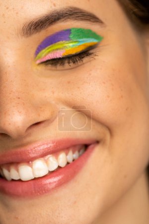 Close up view of smiling teenager with freckles and colorful visage 